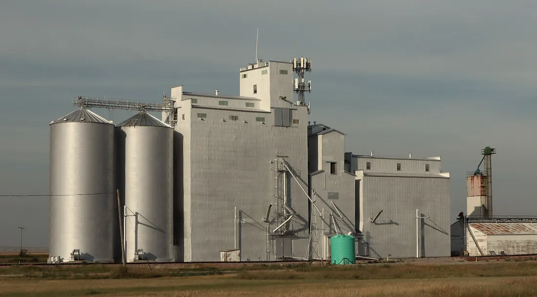 Country grain elevator and steel bins on the open plains under a gray sky